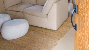 Una sala de estar moderna con un sofá seccional, otomanas, un ventilador de techo y vistas a una piscina y un área de estar al aire libre.