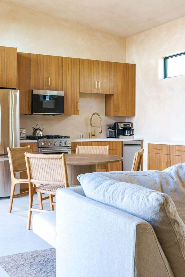 A modern kitchen with wooden cabinets, a dining table, and a sofa.