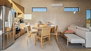 Una cocina moderna con refrigerador de acero inoxidable, armarios de madera y un comedor con sillas de mimbre.