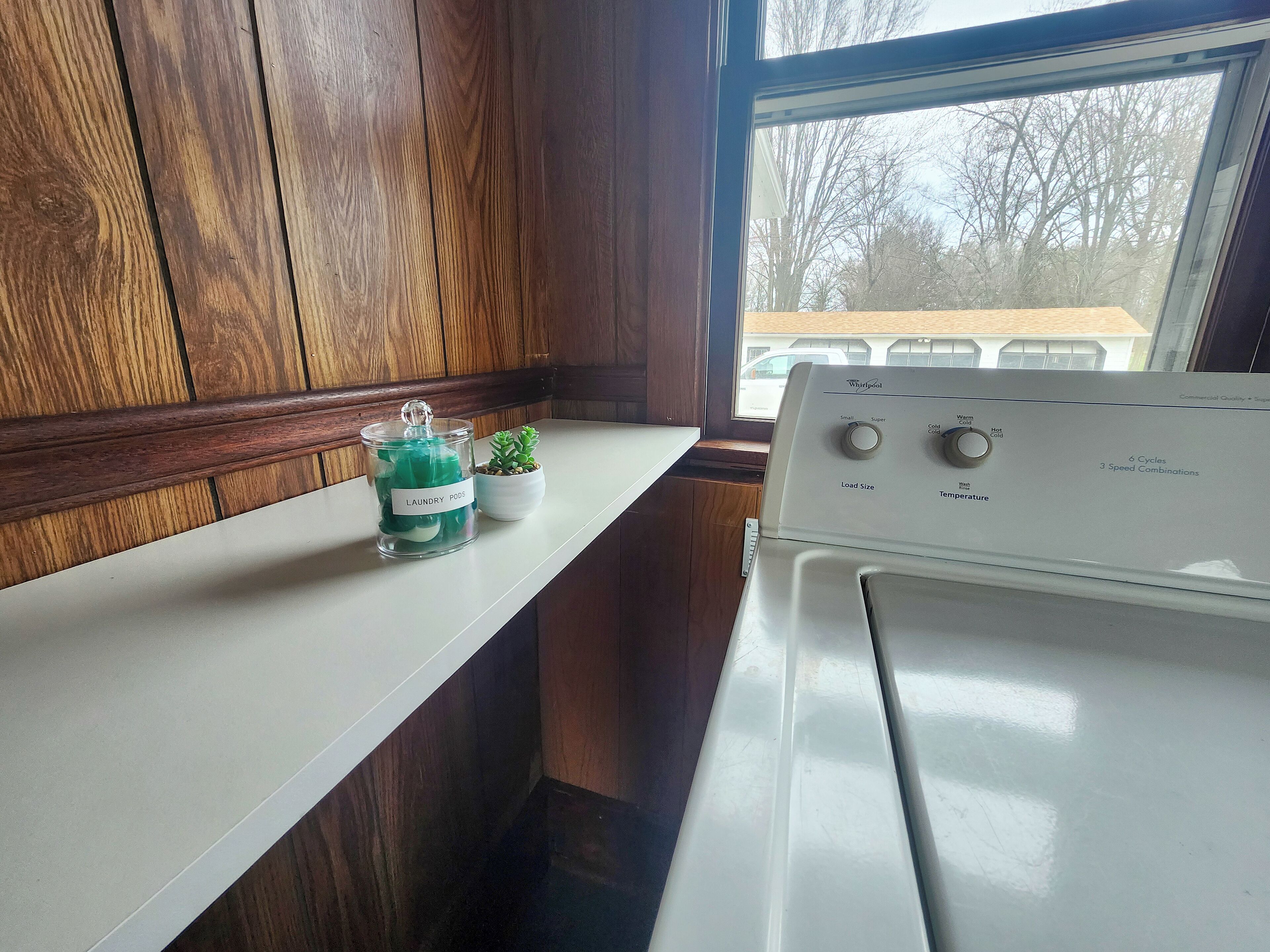 A kitchen with a white stove, wooden cabinets, a window, and a small potted plant on the counter.