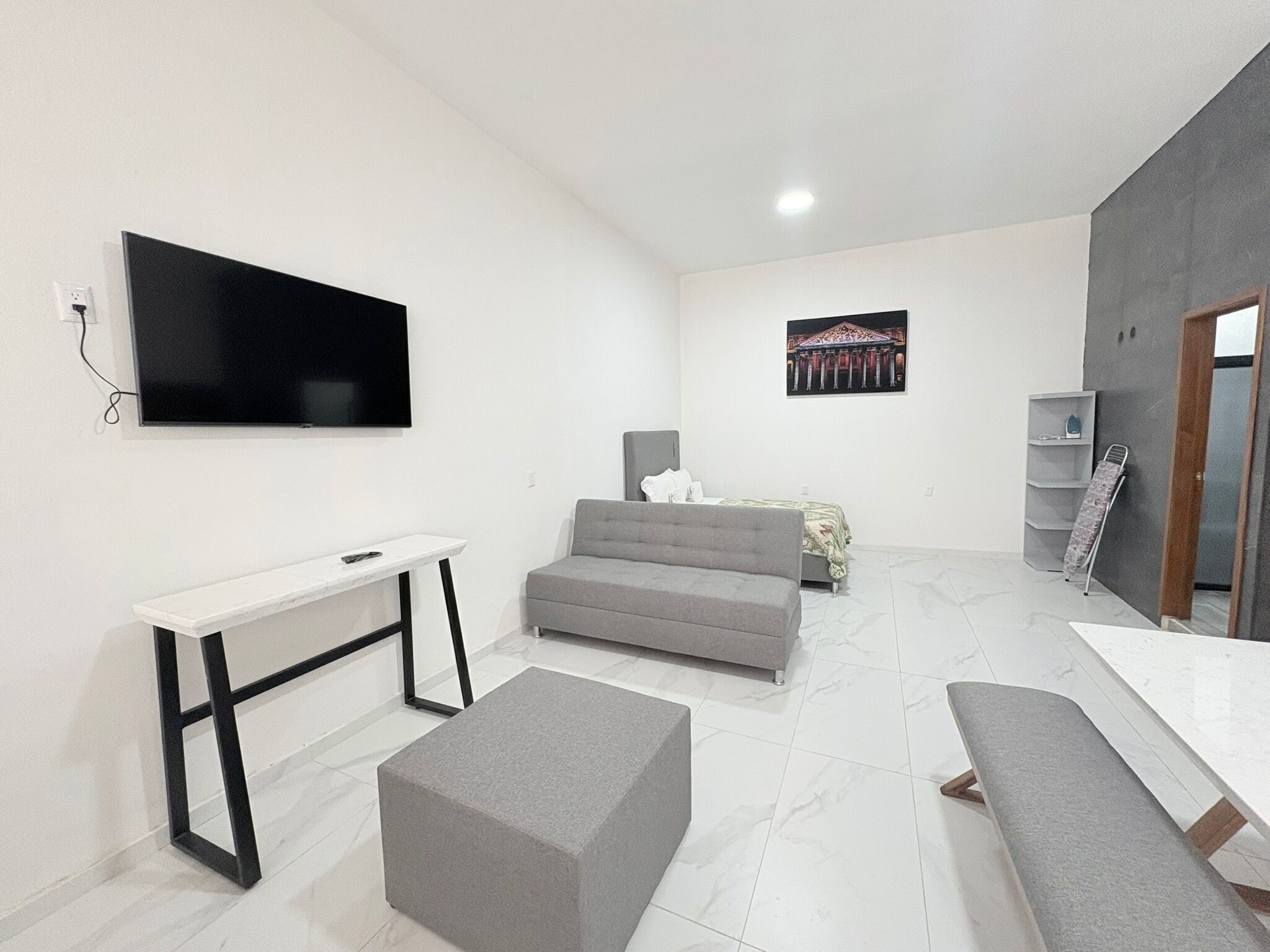 Ein modernes Wohnzimmer mit Fernseher, grauem Sofa und einem kleinen Tisch.