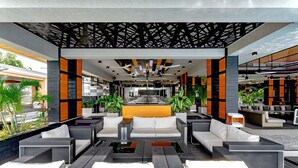 Un espace de détente extérieur moderne, avec des meubles en osier, une table à manger centrale et des plantes en pot.