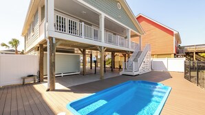 A two-story house with a covered deck and a swimming pool.
