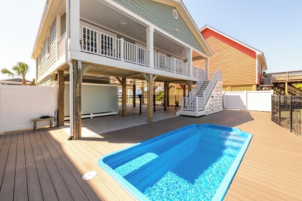 A two-story house with a covered deck and a swimming pool.