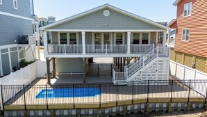 A two-story house with a covered patio and a swimming pool.