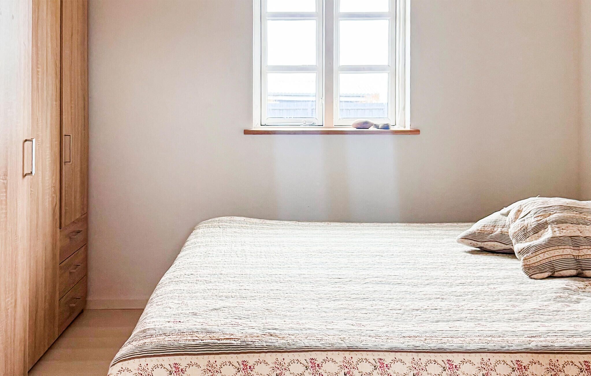 Quarto com cama, janela e guarda-roupa de madeira.