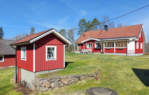A red wooden house with a stone wall and a porch. - Nice home in Vittsjö with sauna (Vittsjö)