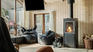A cozy room with a fireplace, a television, and two bean bags. - Lovely home in Ringkøbing with sauna (Ringkøbing)
