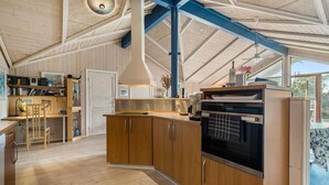 A spacious kitchen with wooden cabinets, a built-in oven, and a large window providing natural light. - Lovely home in Ringkøbing with sauna (Ringkøbing)