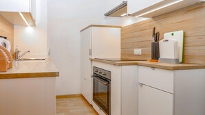 A compact kitchen with a wooden countertop, a built-in oven, and a wall-mounted knife holder. - Ferienwohnung in Sankt Koloman (Sankt Koloman)