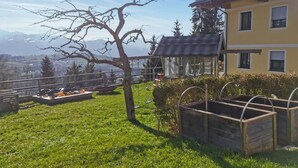 A house with a balcony overlooking a grassy area and mountains. - Ferienwohnung in Sankt Koloman (Sankt Koloman)