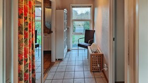 A narrow hallway with a chair and a laundry basket, leading to a window with a view of greenery. - 3 bedroom awesome home in Hjørring (Hjørring)