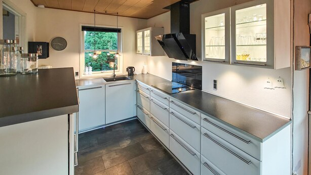 A modern kitchen with white cabinets, a stainless steel countertop, and a window with a view of greenery. - 3 bedroom awesome home in Hjørring (Hjørring)