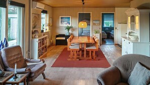 A spacious living room with a wooden dining table, comfortable seating, and a red rug. - 3 bedroom awesome home in Hjørring (Hjørring)