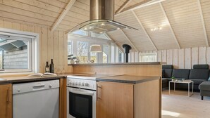 A compact kitchen with a Bosch dishwasher, an oven, and a stove. There is a window providing natural light and a view of the outdoors.