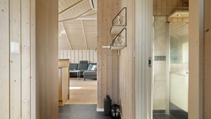 A wooden interior hallway leading to a living area with a sofa and a table.