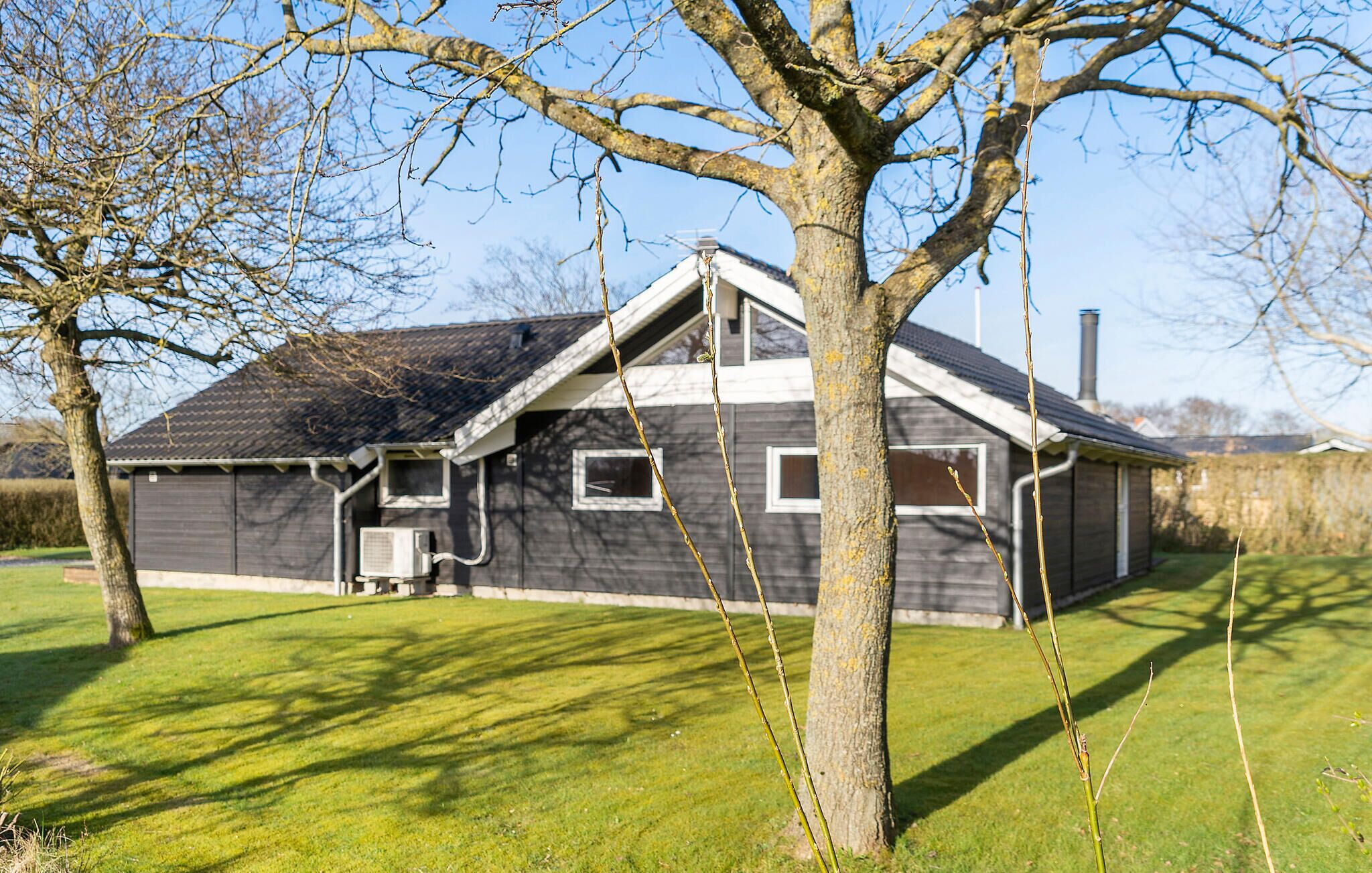 Une maison avec un toit en pente, une cheminée et un appareil de climatisation fixé au mur extérieur.