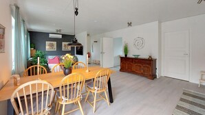 Un'area pranzo con un tavolo e sedie in legno, un vaso con fiori e un mobile contenente oggetti decorativi.