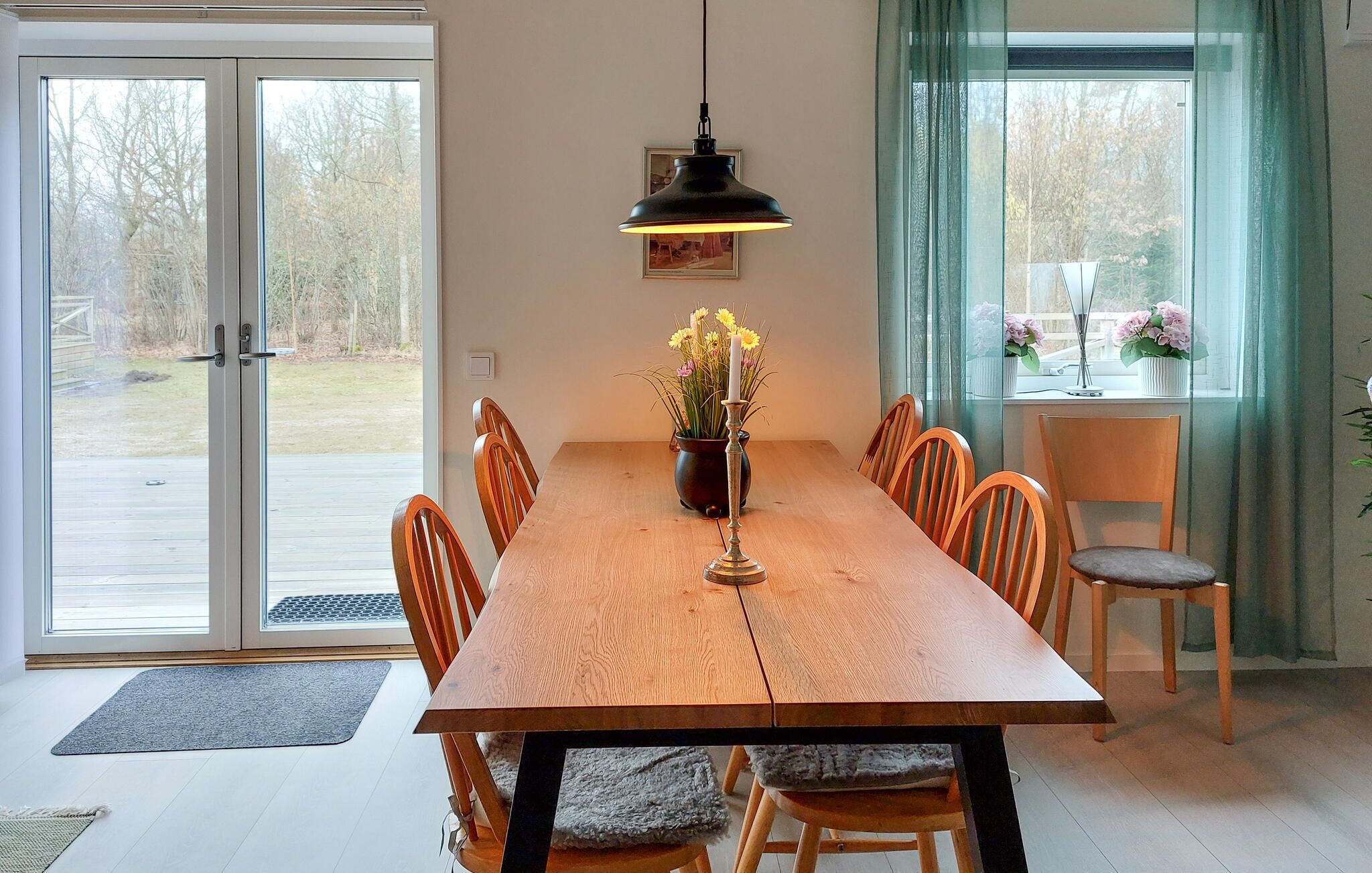 Un coin repas avec une table en bois, des chaises, un centre de table composé de bougies et une suspension.