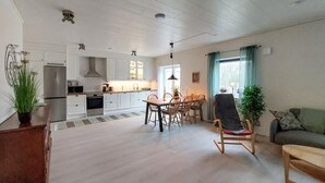Un'ampia zona giorno con tavolo da pranzo, sedie, divano e cucina sullo sfondo.