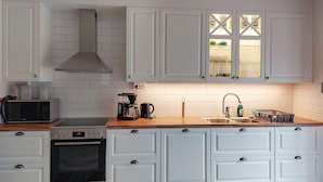 Cucina con mobili bianchi, un forno a microonde, una macchina del caffè e un lavello.