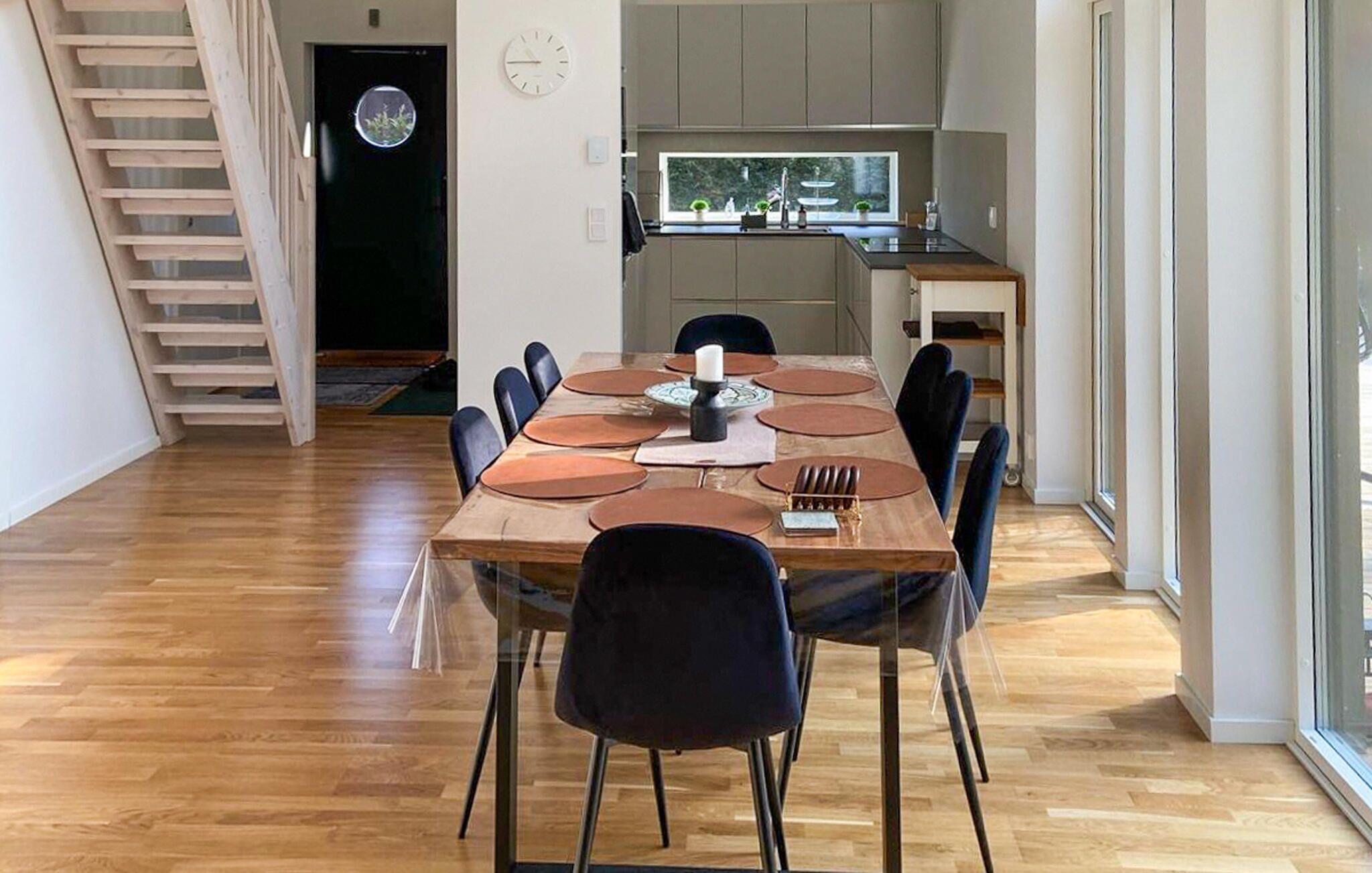A dining area with a wooden table, black chairs, and a kitchen in the background.