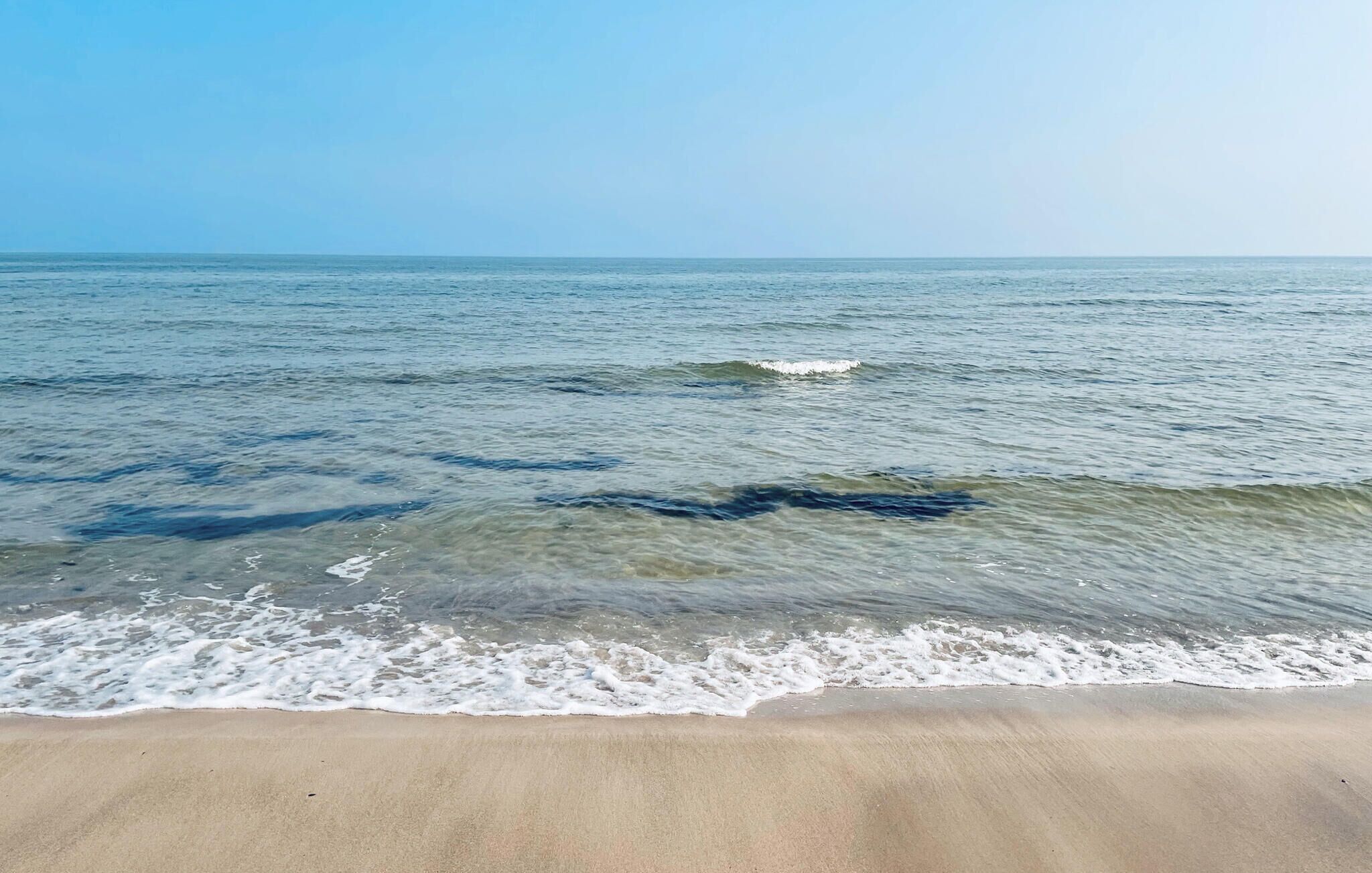 Une plage à l’eau claire et aux vagues douces.