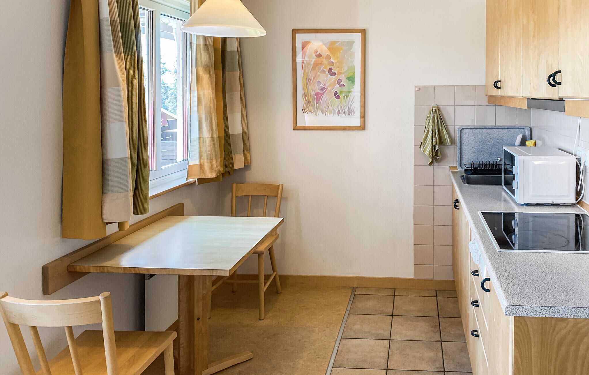 Une petite cuisine équipée d’une table et de chaises, d’un four à micro-ondes et de placards en bois.