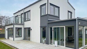 A modern two-story house with large windows, a covered patio, and a visible garden area. - Gorgeous home in Varberg with WiFi (Varberg)