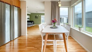 A modern kitchen with a dining area, wooden flooring, and large windows offering a view of the outdoors. - Gorgeous home in Varberg with WiFi (Varberg)