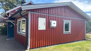 A red metal building with a door, windows, and a utility box. - 1 bedroom stunning home in Mullsjö (Mullsjö)