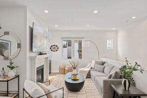 A modern living room with a fireplace, a flat-screen TV, a sofa, and a coffee table. - Stylish Multi-Level Condo with Fireplace & Spacious Living (Santa Barbara)
