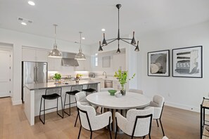 A modern kitchen with a central island, stainless steel appliances, and a dining area with a round table and chairs. - Stylish Multi-Level Condo with Fireplace & Spacious Living (Santa Barbara)