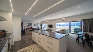 A modern kitchen with a large island, a dining area with a table and chairs, and a living space with a sofa and a TV.