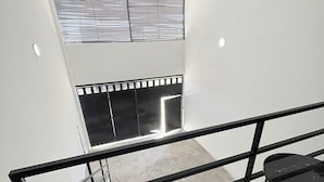 A modern staircase with a glass railing, a black-framed window, and a black-framed table. - Periférico Bodega con Departamento C (Tonalá)