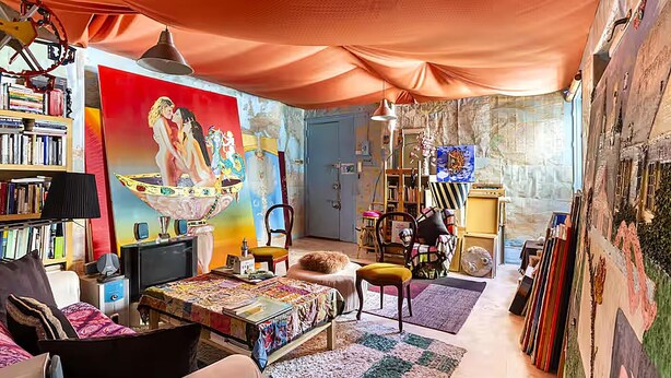 Ein gemütliches Wohnzimmer mit einem großen Gemälde, einer Bücherwand, einem Fernseher und einer bequemen Sitzecke.