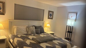 A neatly made bed with a patterned bedspread, two bedside lamps, a nightstand, and a floor lamp.