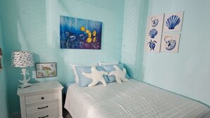 Une chambre à coucher avec un lit, une table de chevet et un tableau représentant des poissons accroché au mur.