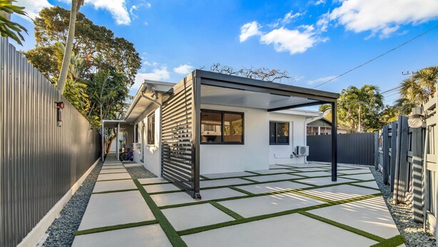 A modern house with a covered patio, a concrete pathway with green accents, and a metal fence. - La Bella vacations 2 (Fort Lauderdale)