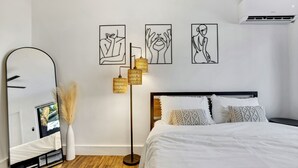 A modern bedroom with a large bed, a floor lamp, a mirror, and wall art. - La Bella vacations 2 (Fort Lauderdale)