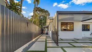 A modern residential building with a narrow driveway, a metal fence, and a well-maintained lawn. - La Bella vacations 2 (Fort Lauderdale)