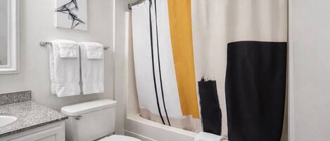 Un baño con inodoro, lavabo y cortina de ducha.