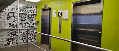 Un ascensor con un indicador de número, una barandilla de metal y grafitis en las paredes.
