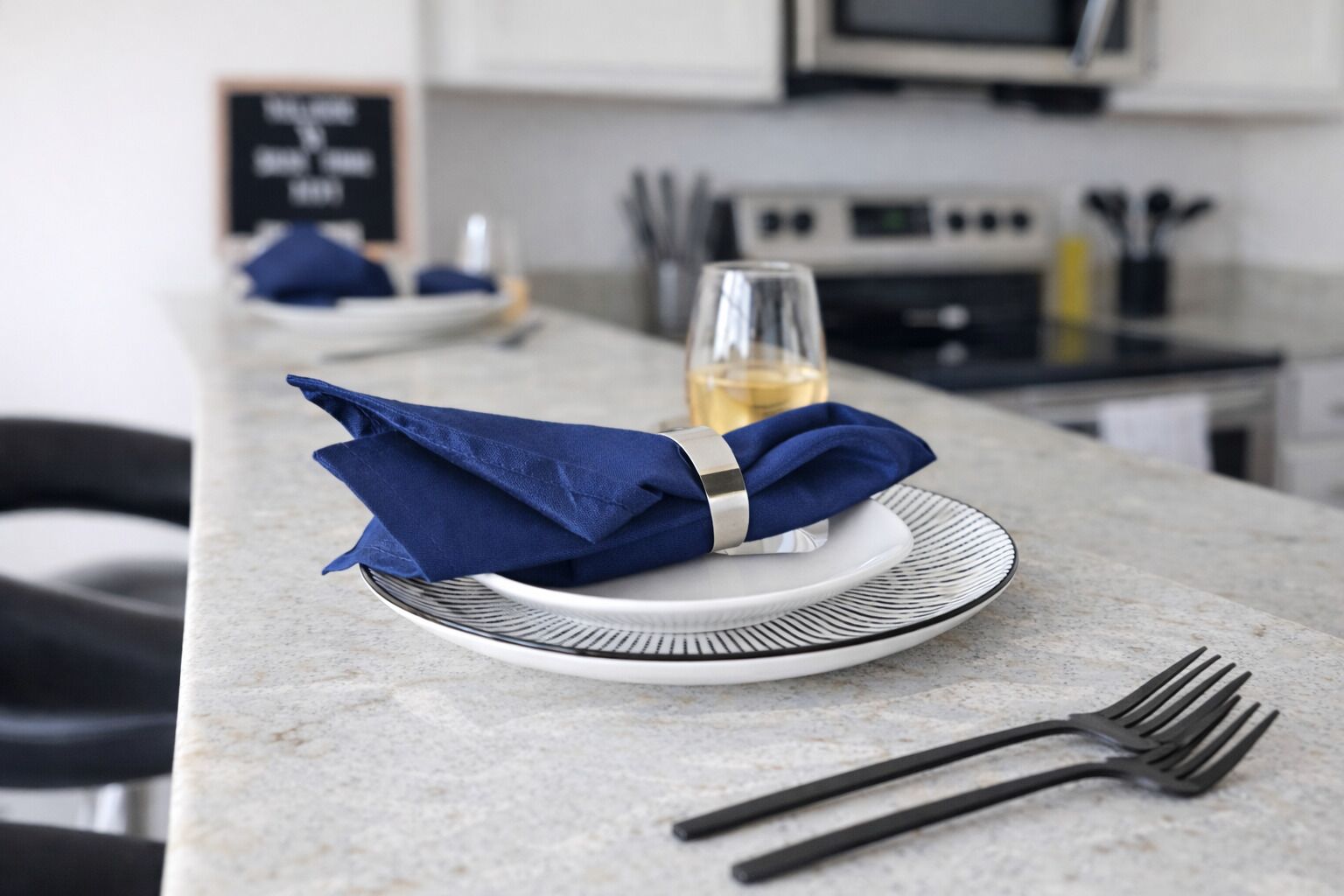 Une table à manger avec une serviette pliée, un verre de vin et des couverts.
