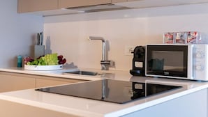 Eine moderne Küche mit integriertem Mikrowellenherd, Spüle und einer Arbeitsplatte mit Schneidebrett und Gemüse.