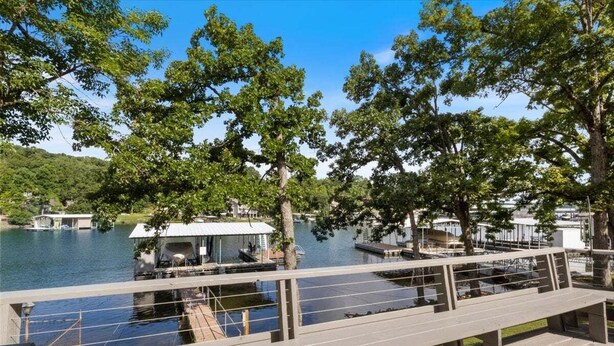 A wooden deck overlooking a lake with docked boats and a covered area.
