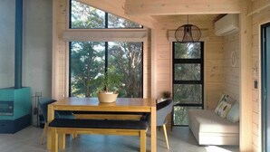 Un interior moderno con techo de madera, ventanas amplias, una mesa de comedor con sillas y un sofá.