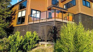 Una casa moderna de dos pisos con amplios ventanales, un balcón y fachada de madera.