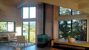 Una habitación amplia con un gran ventanal, chimenea, una mesa de comedor y una zona de estar.