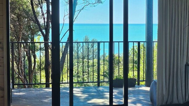 Habitación con vista al mar a través de una puerta corrediza de vidrio.